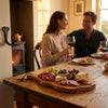 The Alba Olive Wood Board with Leather Loop in use on a dining table