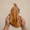 The Alba Olive Wood Board with Leather Loop held in two hands, showing its size