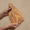 The Alba Olive Wood Paddle Board held in two hands, showing its size