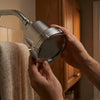 The filtered shower head mounted on the wall arm of a guest bathroom