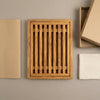 The Alba Olive Wood Bread Board with Crumb Tray with its kraft wrapping and plain shipping box