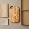 The Alba Olive Wood Board with Grip Hole with its kraft wrapping and plain shipping box